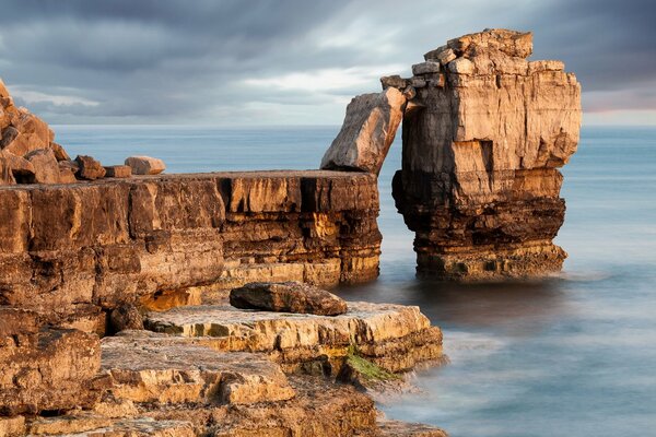 Paysage avec un rocher de la mer et un ciel sombre