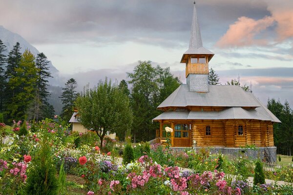 Maison en bois avec des parterres de fleurs en été