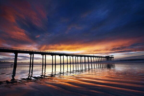 Beautiful sunset on the background of the bridge by the sea