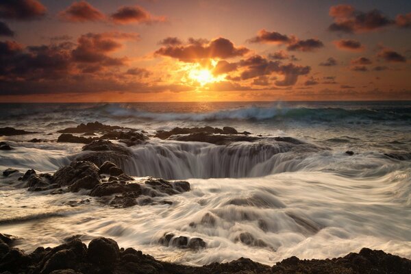 Waterfall funnel in the sea at sunset