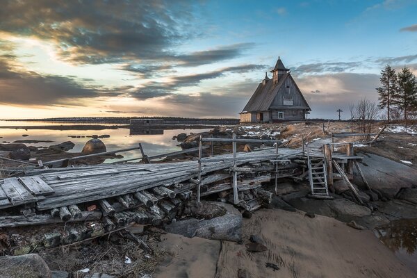 Wooden church. Wooden bridge. Sunset on the river