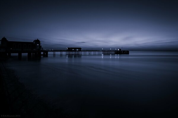 Mer de nuit calme. Jetée avec des lumières au crépuscule