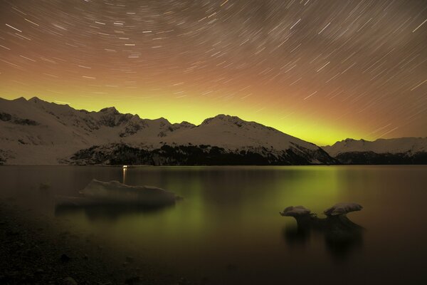 Paisaje nocturno del lago rodeado de montañas nevadas