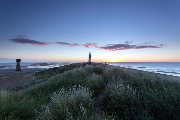 Faro solitario al atardecer en el borde del agua