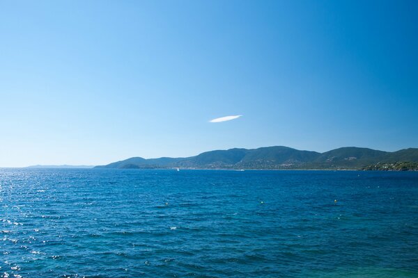 Clear sky over the sea and a view of the green hilly coast