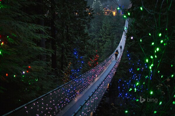 People cross the suspension bridge with festive lights