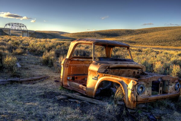 An old car in a field at sunset