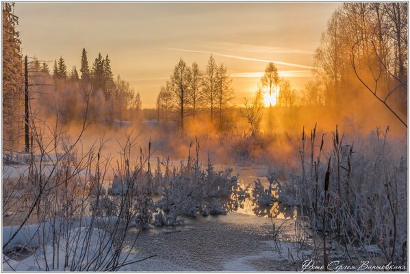 Puesta de sol de invierno, noche en el río en las heladas