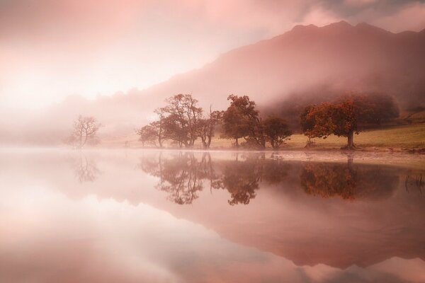 Brume rose sur le lac dans les montagnes