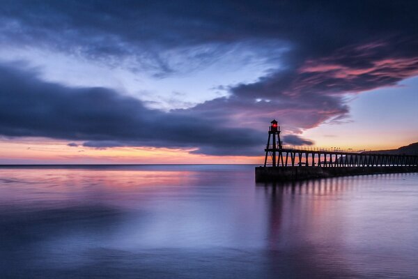 In the middle of the sea you will see a pier and a lighthouse