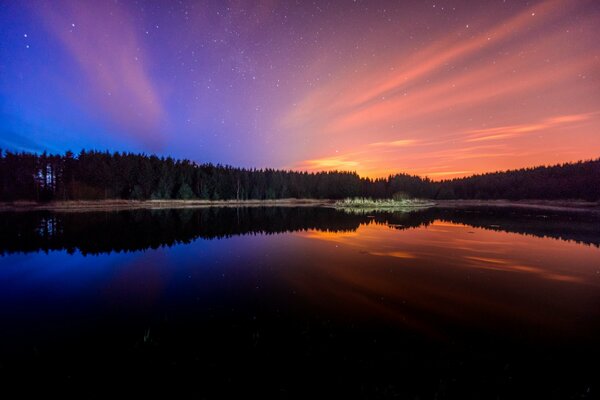 Trees are reflected in the water at sunset