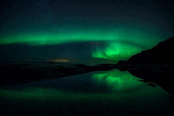 Das Nordlicht spiegelt sich im Wasser wider