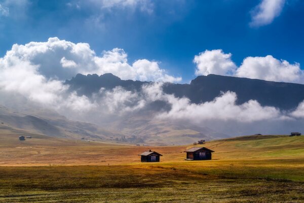 Im Tal stehen zwei Häuser vor dem Hintergrund der riesigen Berge