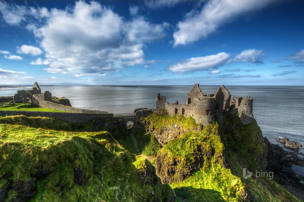 Irlanda del Norte Condado de Antrim. Color celeste sobre el fondo de las ruinas. Ruinas en las rocas