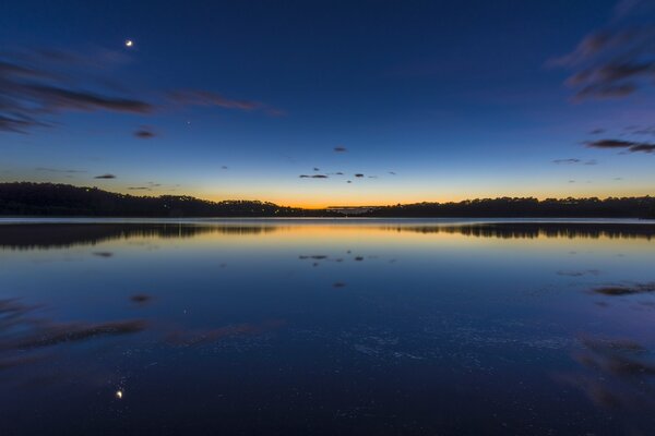 Ein Dämmerungssee mit einem Spiegelbild des dunklen Himmels