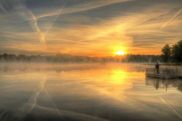 Paisaje con lago y puesta de sol en medio de la niebla