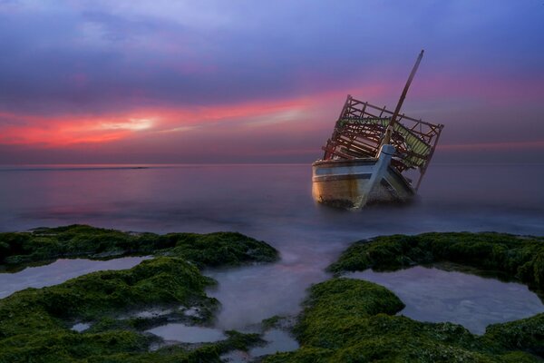 Abandoned ship at sea at sunset