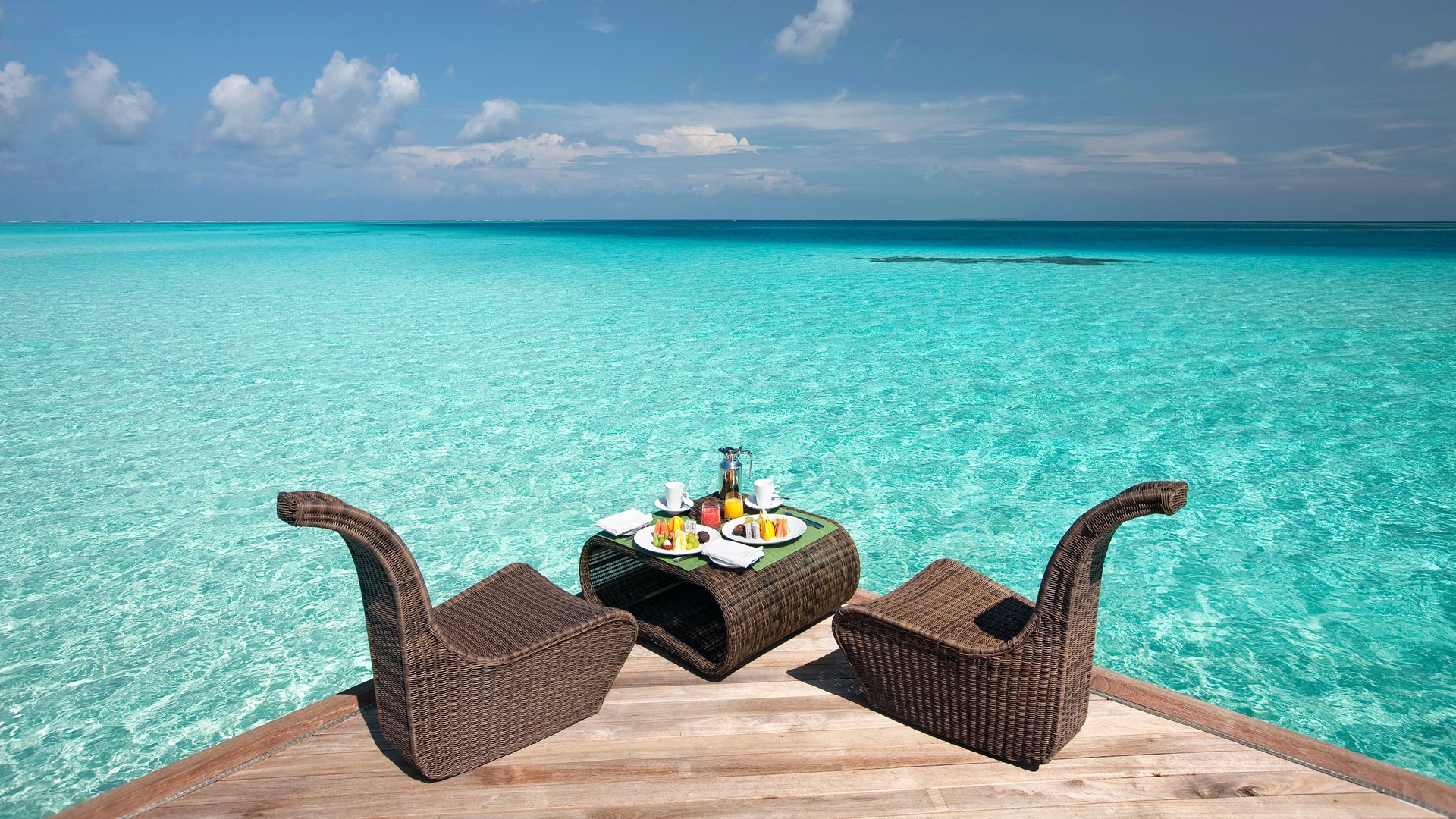 ocean water pier table chairs food sky clouds horizon