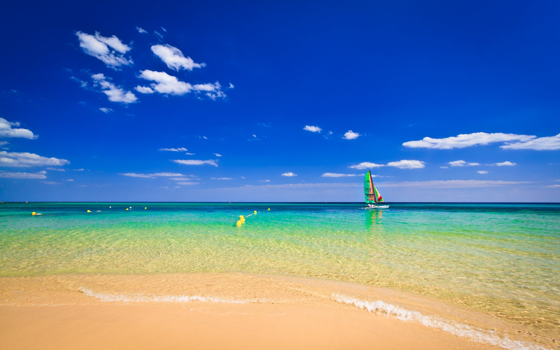 océano playa arena boyas barco cielo nubes horizonte