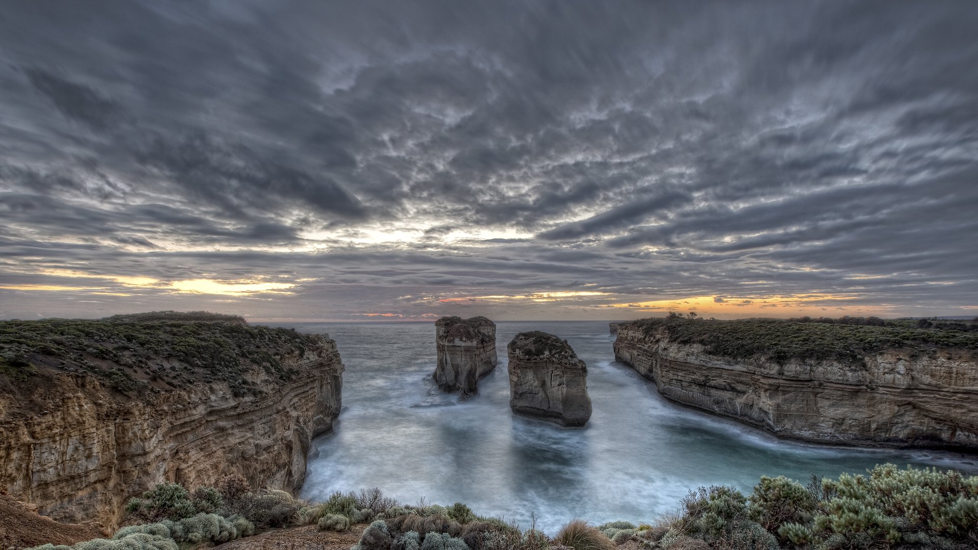 bahía rocas agua plantas cielo nubes