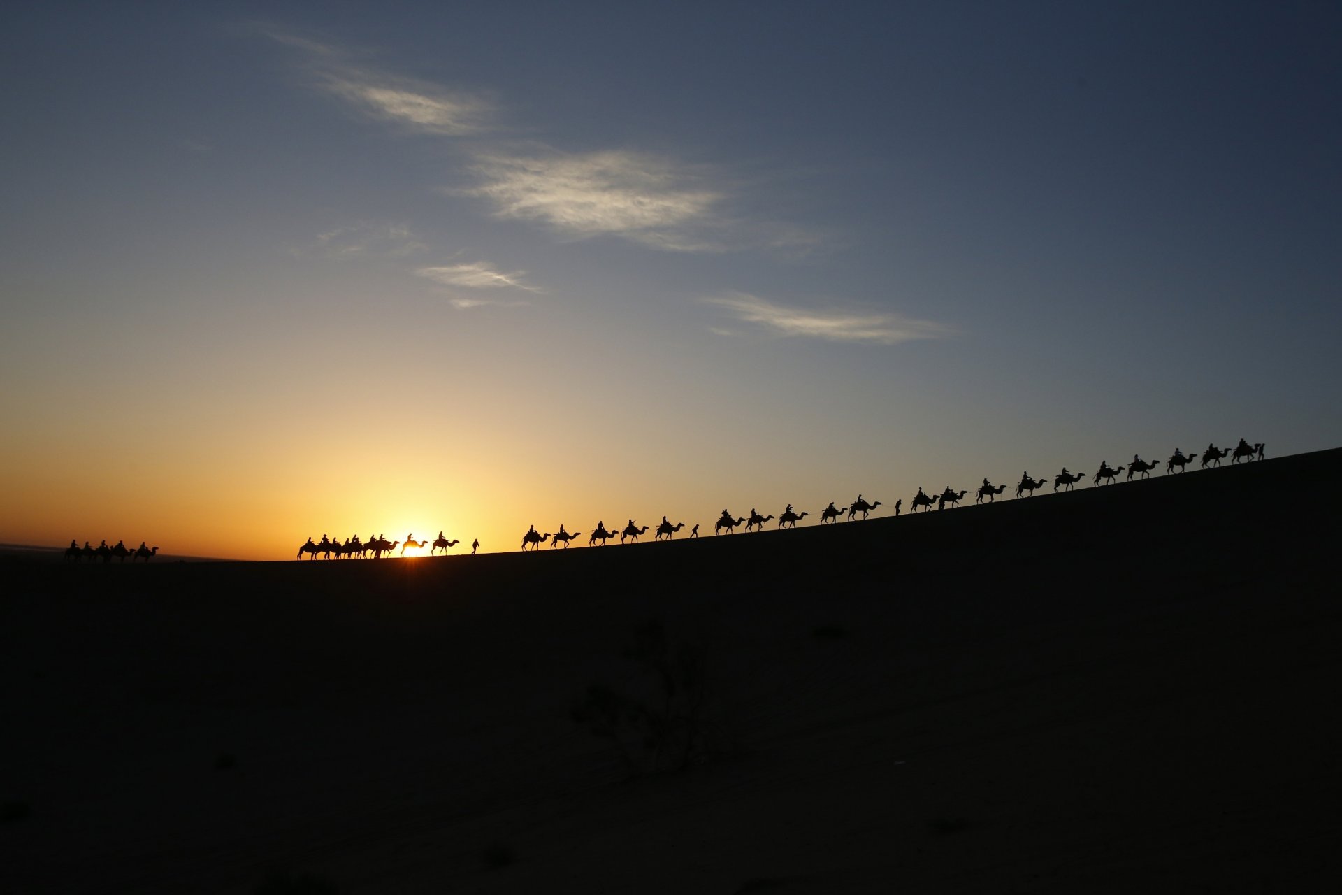 caravana camellos gente sol cielo nubes desierto