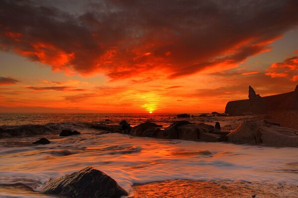 Tramonto cremisi sul mare. Spiaggia sabbiosa