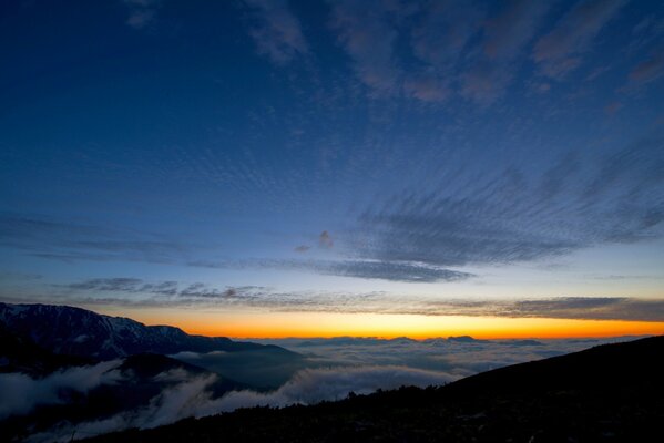 Sunset in the mountains above endless clouds