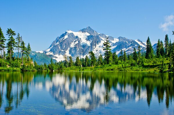 El lago refleja el bosque verde en las montañas azules