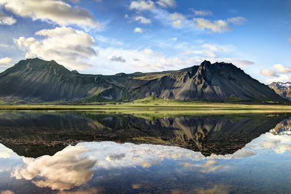 Il paesaggio delle colline di montagna si riflette nella superficie a specchio del Lago