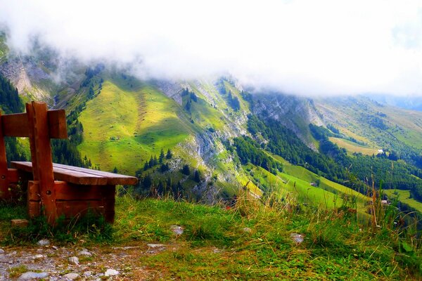 A bench under the clouds on the edge of the mountain