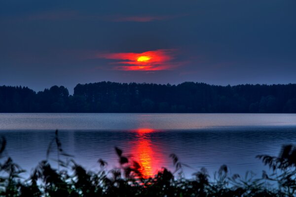 Reflexion eines blutigen Sonnenuntergangs im Wasser