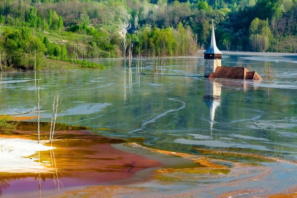 Una chiesa affogata nel lago circondata dall acqua e dalla foresta