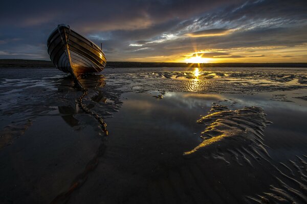 Bateau échoué au bord de la mer au coucher du soleil
