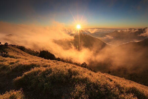 La niebla de la mañana en las montañas en el fondo del sol naciente