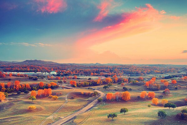 Valle con case e alberi al tramonto in autunno