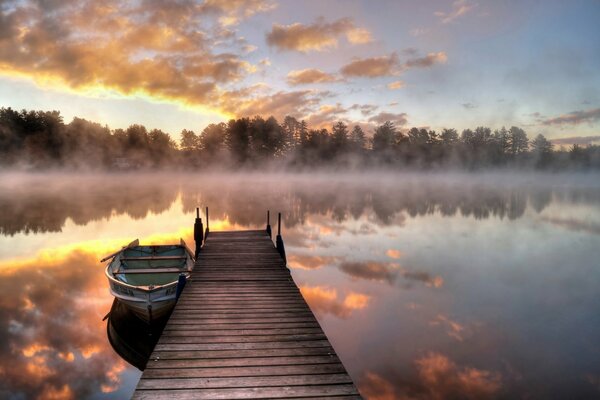 Brücke und Boot am See im Morgennebel