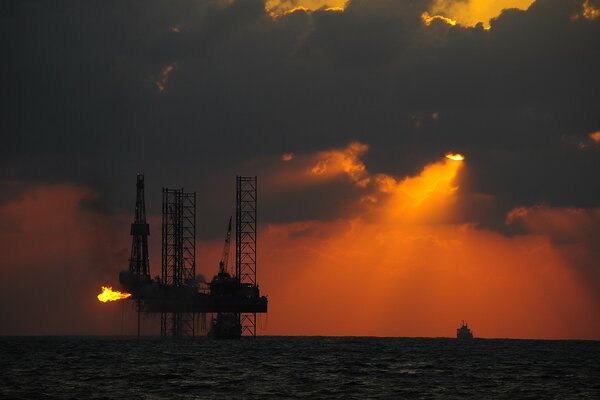 Tramonto su una piattaforma petrolifera in mare blu